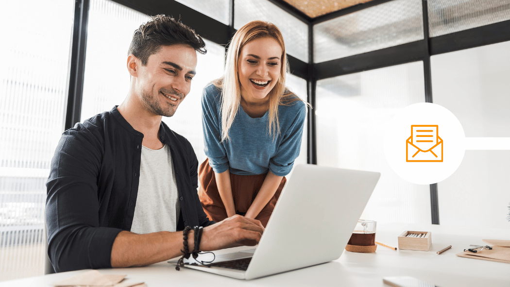 Colleagues looking at laptop and smiling in office