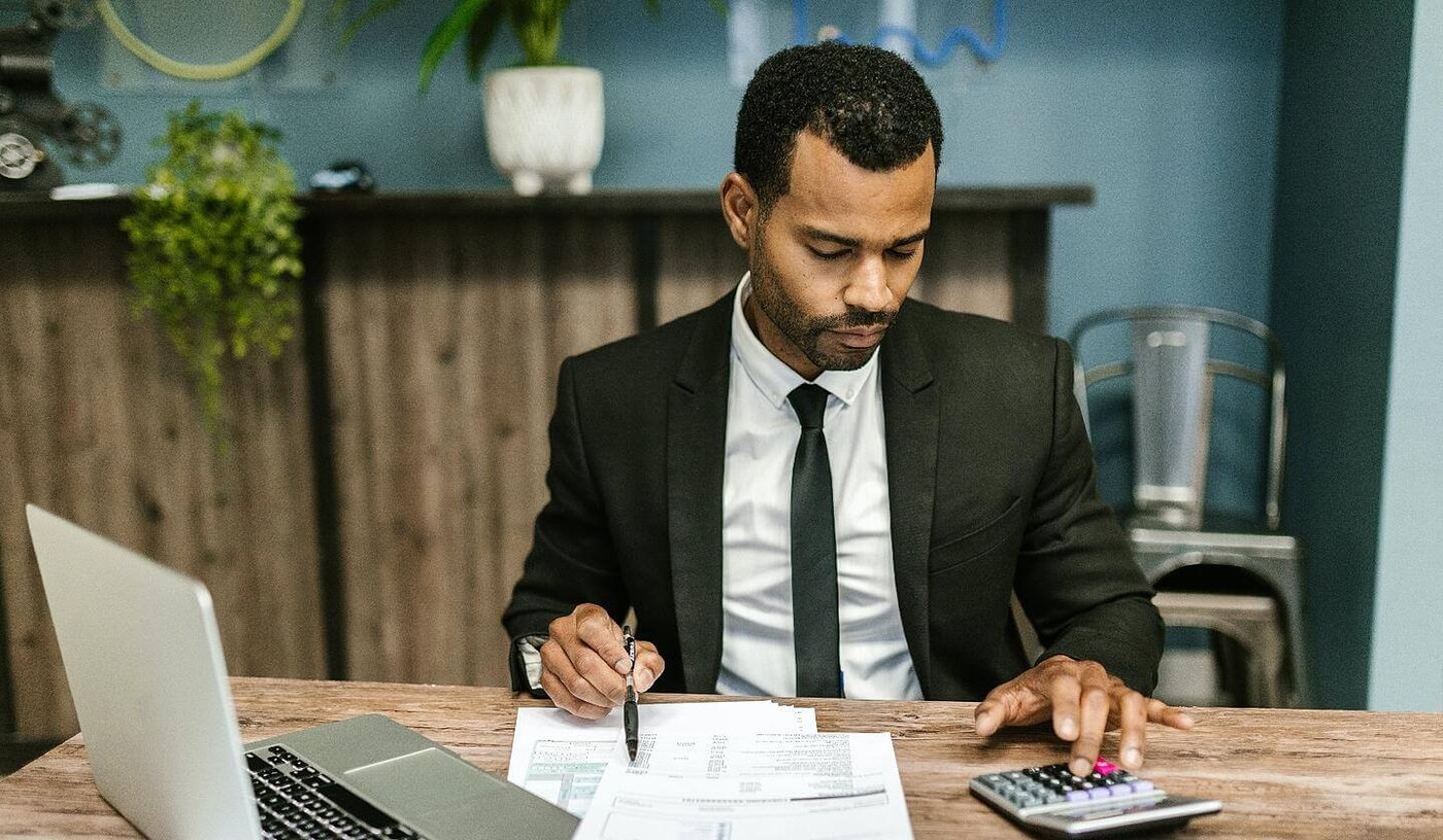 Financial adviser using calculator at desk in office