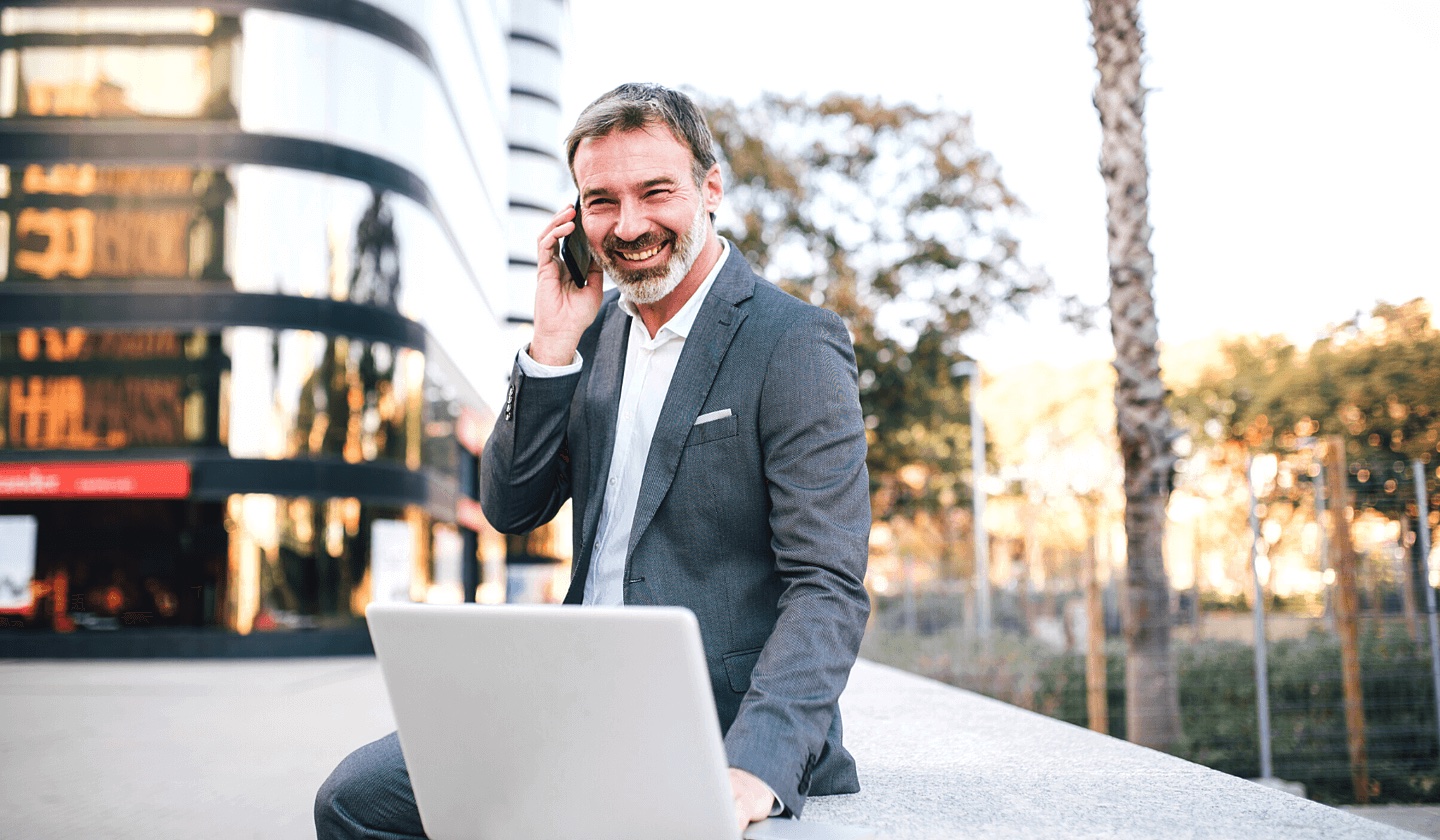 financial services leader sitting on wall with laptop and phone