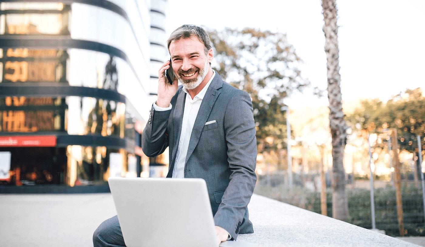 financial services leader sitting on wall with laptop and phone