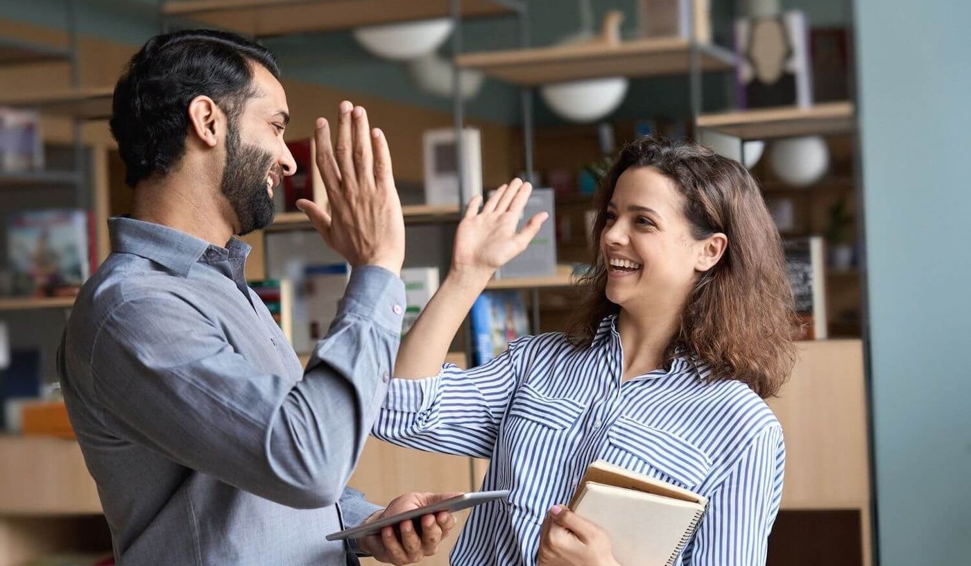 Colleagues high five in office after success