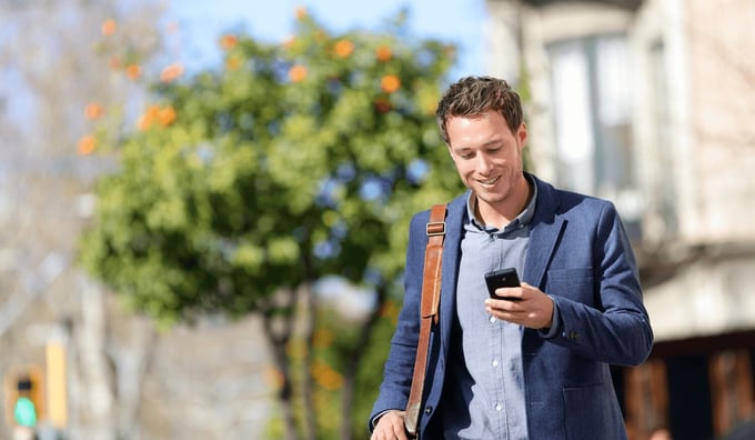 Professional Man In A Suit Looking At Phone In Street Smiling