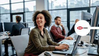 Woman typing on laptop and smiling in office with colleagues