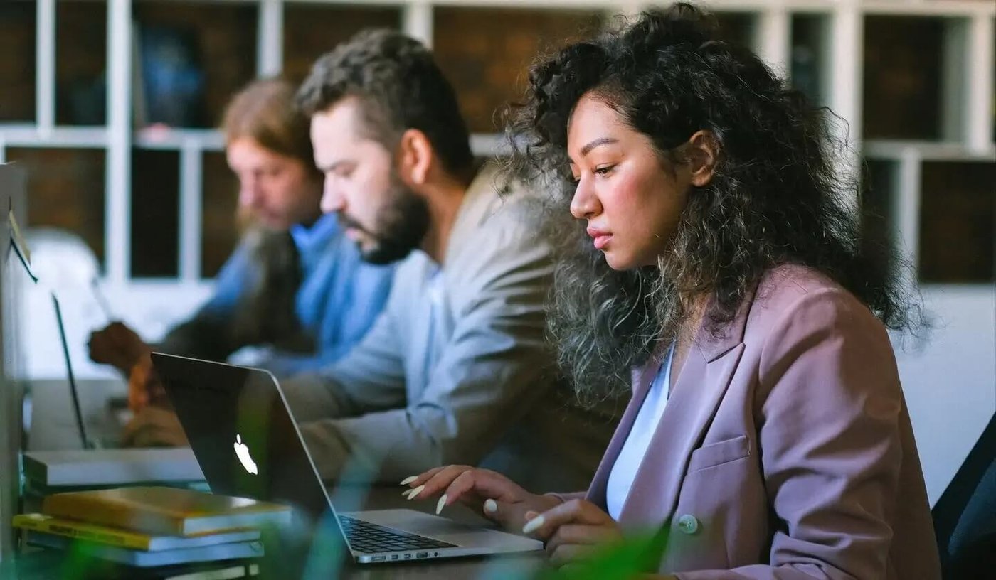 Woman working on laptop next to colleagues looking worried