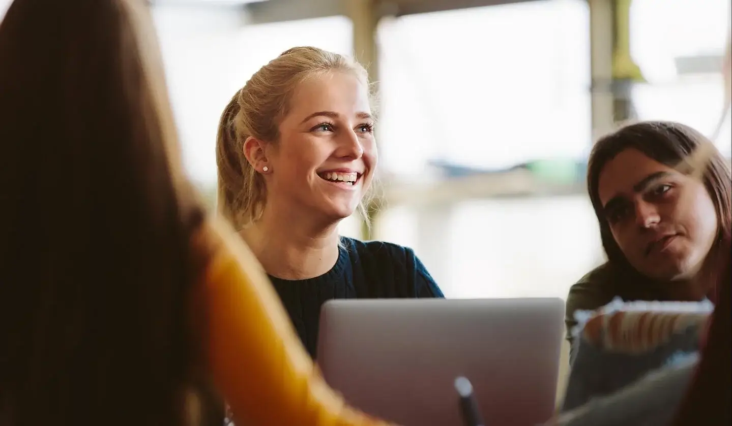 Young woman on laptop in office with team