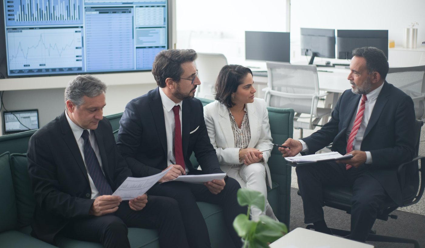 Business professionals gather on a sofa to hear presentation from colleagues