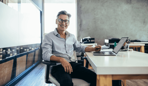 Business man at desk smiling and looking at the camera