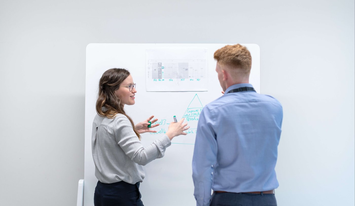 Man and woman talk in front of whiteboard