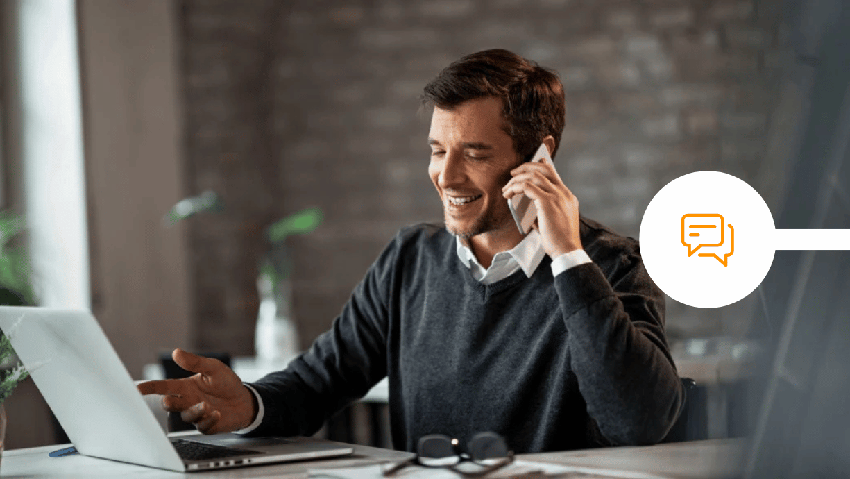 Man sitting at desk on the phone and using his laptop